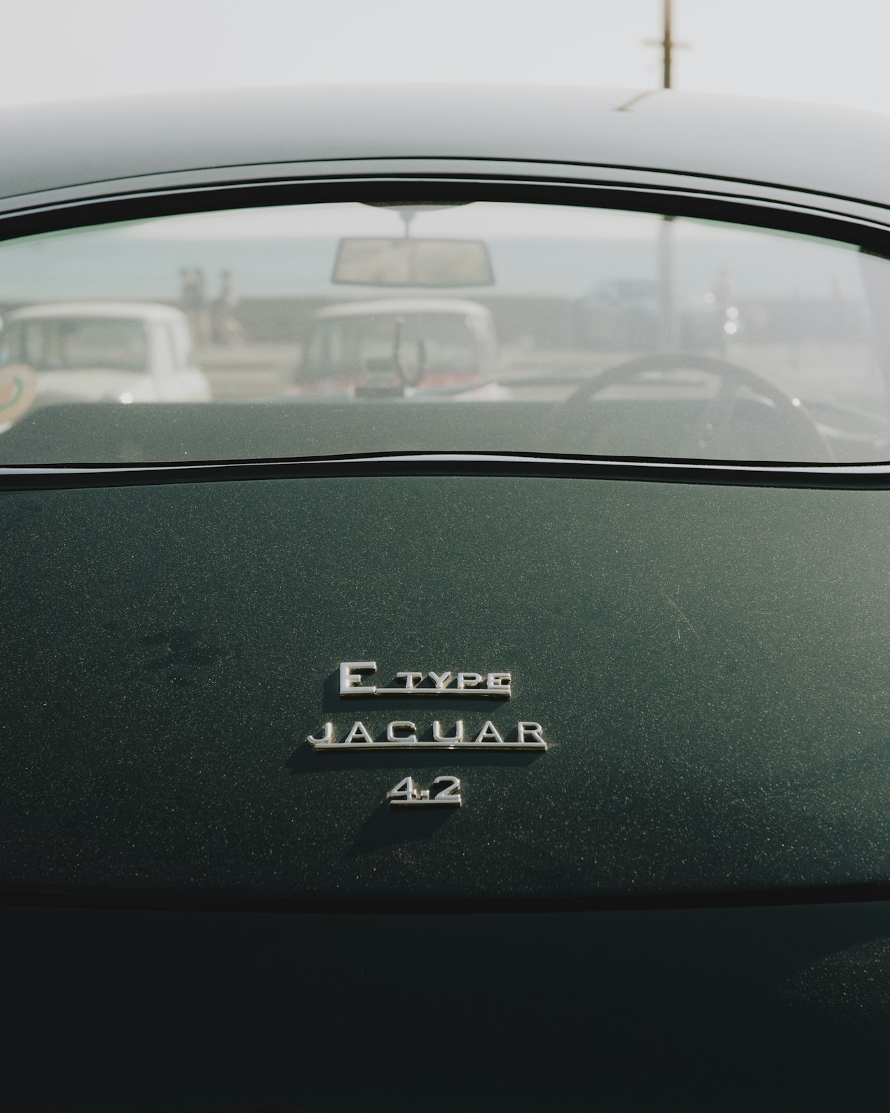 Jaguar E-Type close-up detail in British racing green, showing the iconic bonnet and headlight design